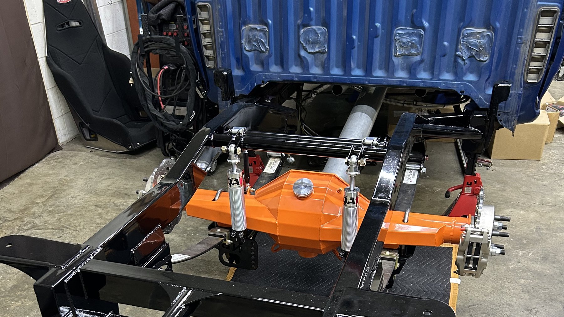 The narrowed rear frame and Chevy-orange 9-inch axle, mid-build